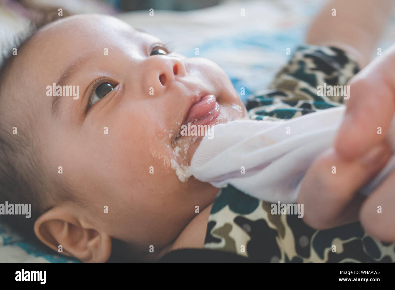 asian mother is wiping her baby's face after infant baby boy vomiting