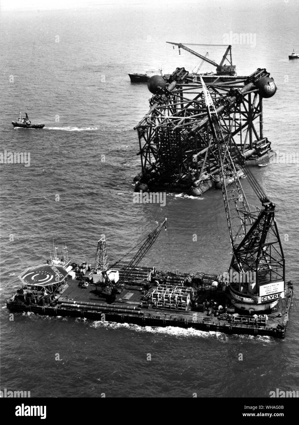 Jacket section of production platform 'Graythorp I' on site on BP's Forties oilfield in the North Sea, before lowering to the sea bed, with crane barge 'Hercules' in foreground. July 1974 Stock Photo