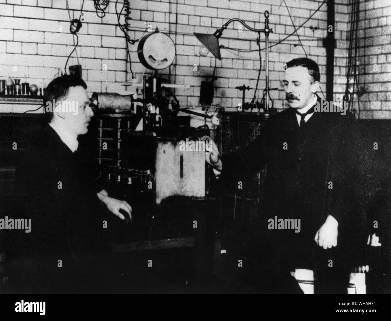 Hans Geiger 1882-1945 and Ernest Rutherford 1871-1937 in the laboratory in Manchester University where they found that alpha particles were the nuclei of helium atoms and that beta rays were particles travelling at very high speeds. Stock Photo