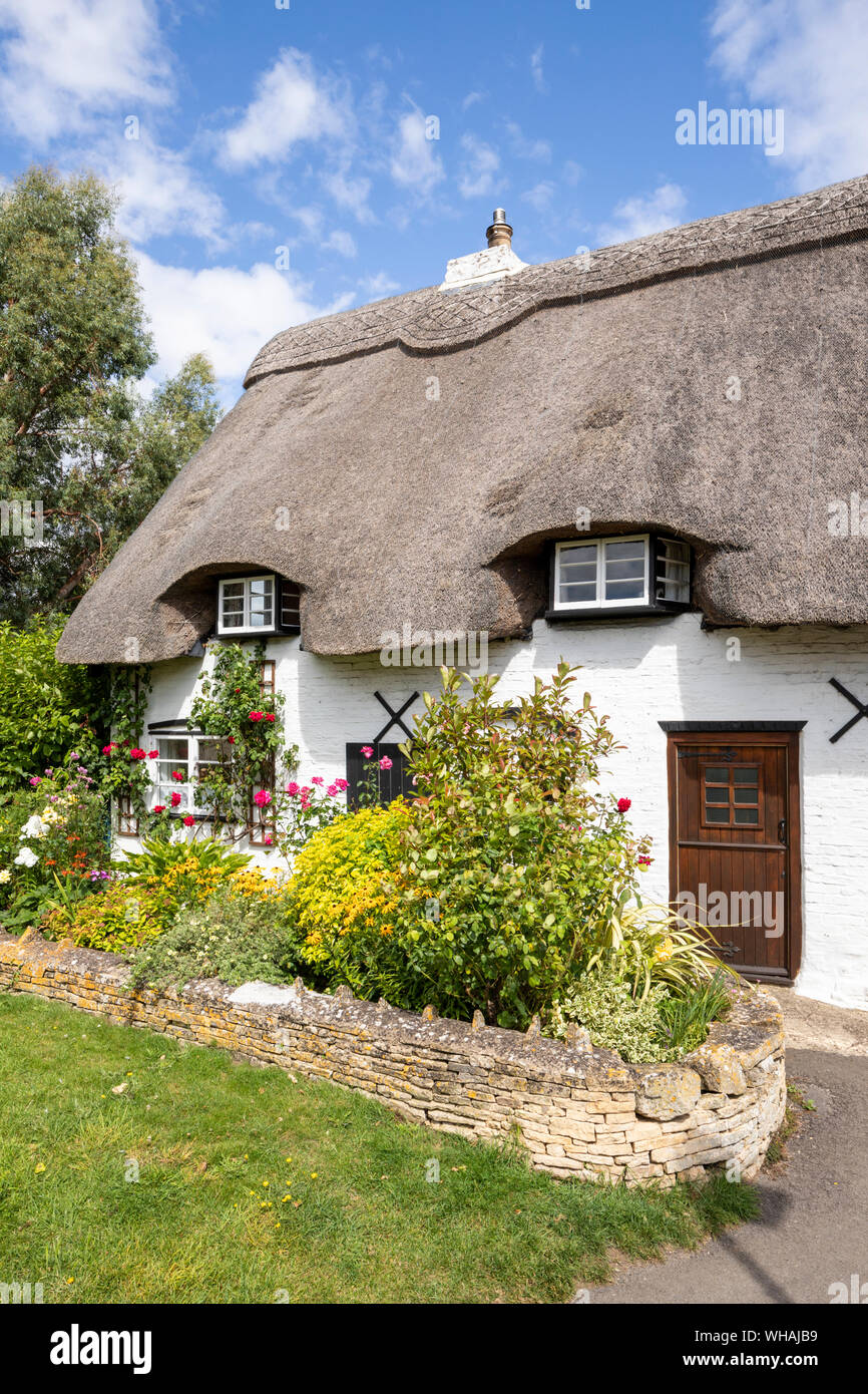 The delightful, thatched Church Cottage in a corner of the churchyard at Bishop's Cleeve, Gloucestershire UK Stock Photo