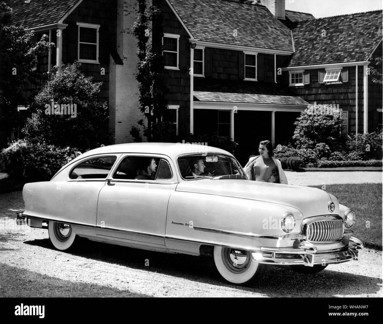 1951 Nash. The luxurious Ambassador 2 door sedan. couple in the car talking to woman outside large house. . USA. . Stock Photo