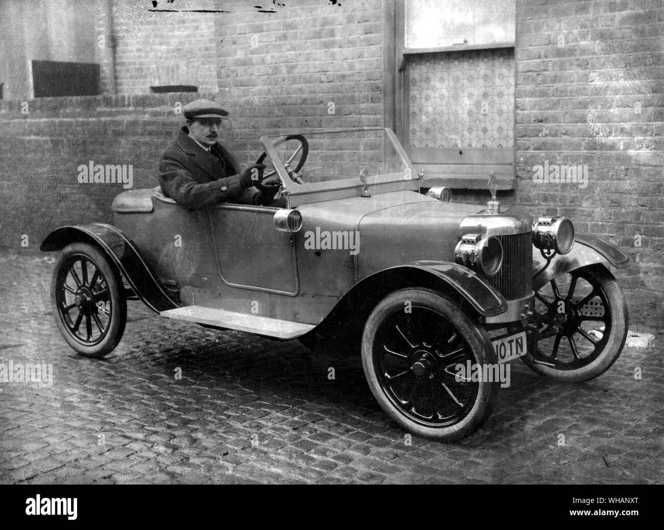 1913 Lagonda G F Oates at the wheel. In 1913, Gunn scrapped his previous models and decided to adopt just one line, an 1100cc 11.1 hp car with unit-construction gearbox and transverse front suspension, a marketing policy and design clearly inspired by the Ford Model T. Another progressive feature was the integral body/chassis construction. . Stock Photo