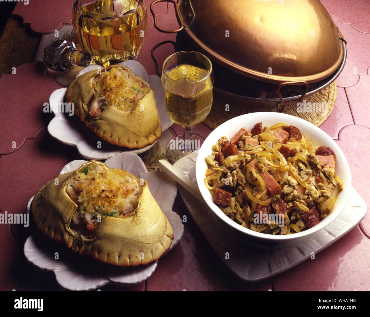 International Cooking . Left, Devilled Crab.. USA.. Right, Steamed Clams With ham And Sausages.. Ameijoas Na Cataplana, Portugal. Stock Photo