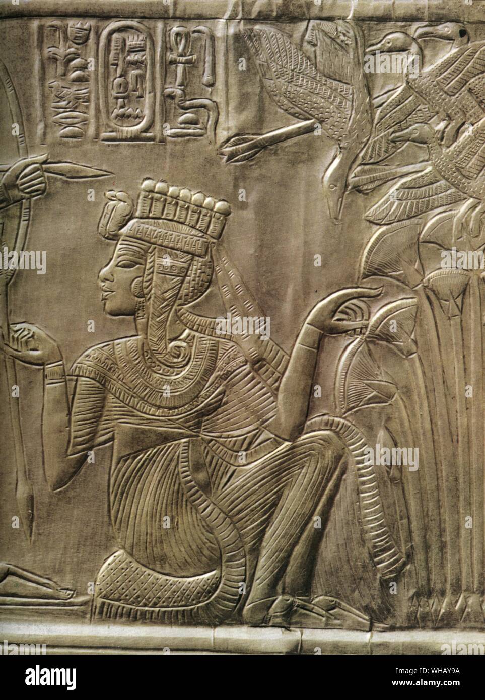 Detail of the gilded shrine showing the Queen Ankhesenamun at the feet of the king. Tukankhamen, by Christiane Desroches Noblecourt, page 251.. The external walls and the doors of the shrine are subdivided into panels framed by hieroglyphic inscriptions with scenes showing Tutankhamun and his wife in various aspects of married life, a theme that recalls the scenes of the Amarna Period. The entire decorative scheme of the shrine has strong symbolic connotations associated with the religious and political spheres. The intimate ties between the pharaoh and his bride represent the serene Stock Photo