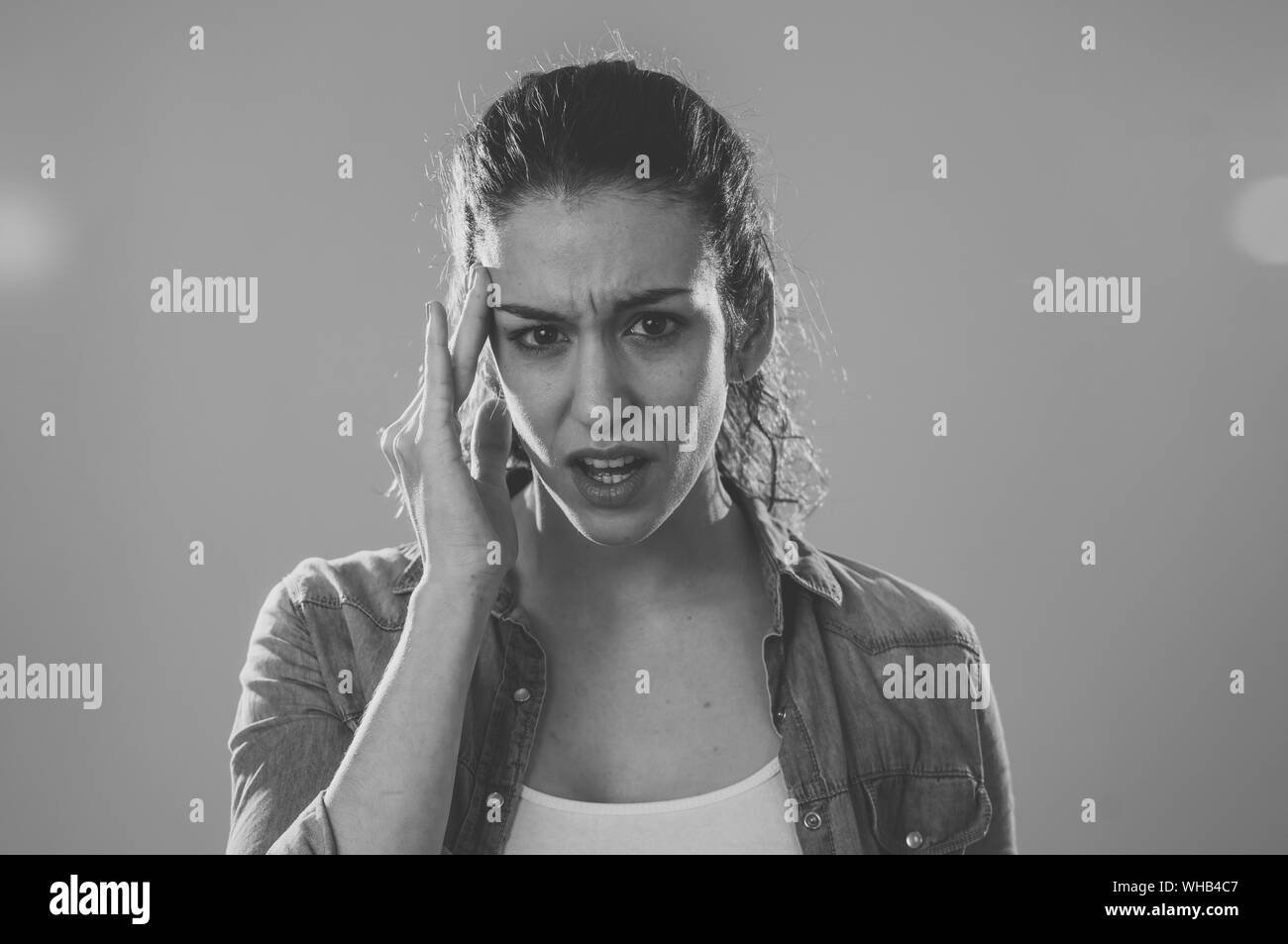 Close up portrait of a young woman looking worried and thoughtful suffering from migraines in great pain. Isolated on neutral background. In facial ex Stock Photo