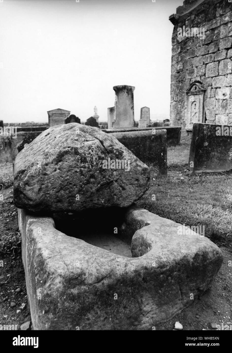 The stone hollowed in the form of Martha Wishart at Tullibody. .. On the North side of the Auld Kirk is the Maiden Stone, the stone coffin in which the Maid was laid to rest.. the priest of Tullibody, Peter Beaton, is said to have got the Myretoun Maid, Martha Wishart, pregnant. Martha was the daughter of the Laird of Myretoun The priest, after completely winning the damsels affections, proved insincere. He is said to have been lured by the prospect of ecclesiastical advancement and broken his vows to the maid. The maid died of a broken heart because of the affair. On her death-bed she gave Stock Photo
