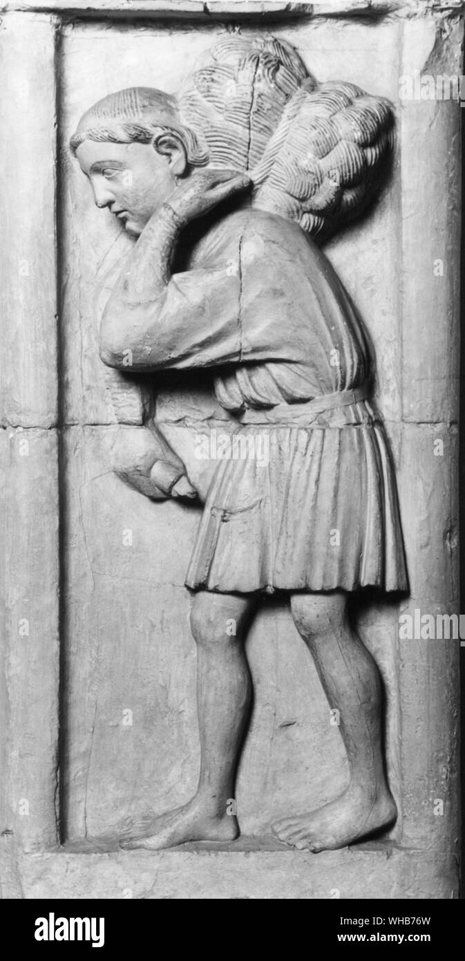 14th Century sculpture in Moisson showing a man carrying a bundle. Stock Photo