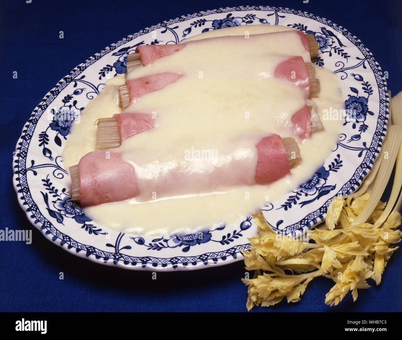 Celery sticks wrapped in ham with a savoury white sauce poured over.. Stock Photo