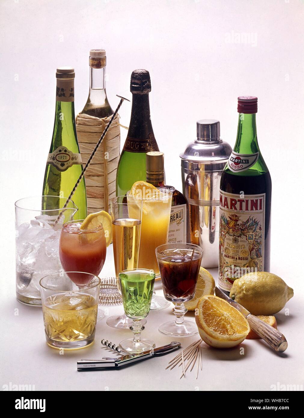 Assorted alcoholic drinks in bottles and glasses with surrounding paraphernalia. Stock Photo