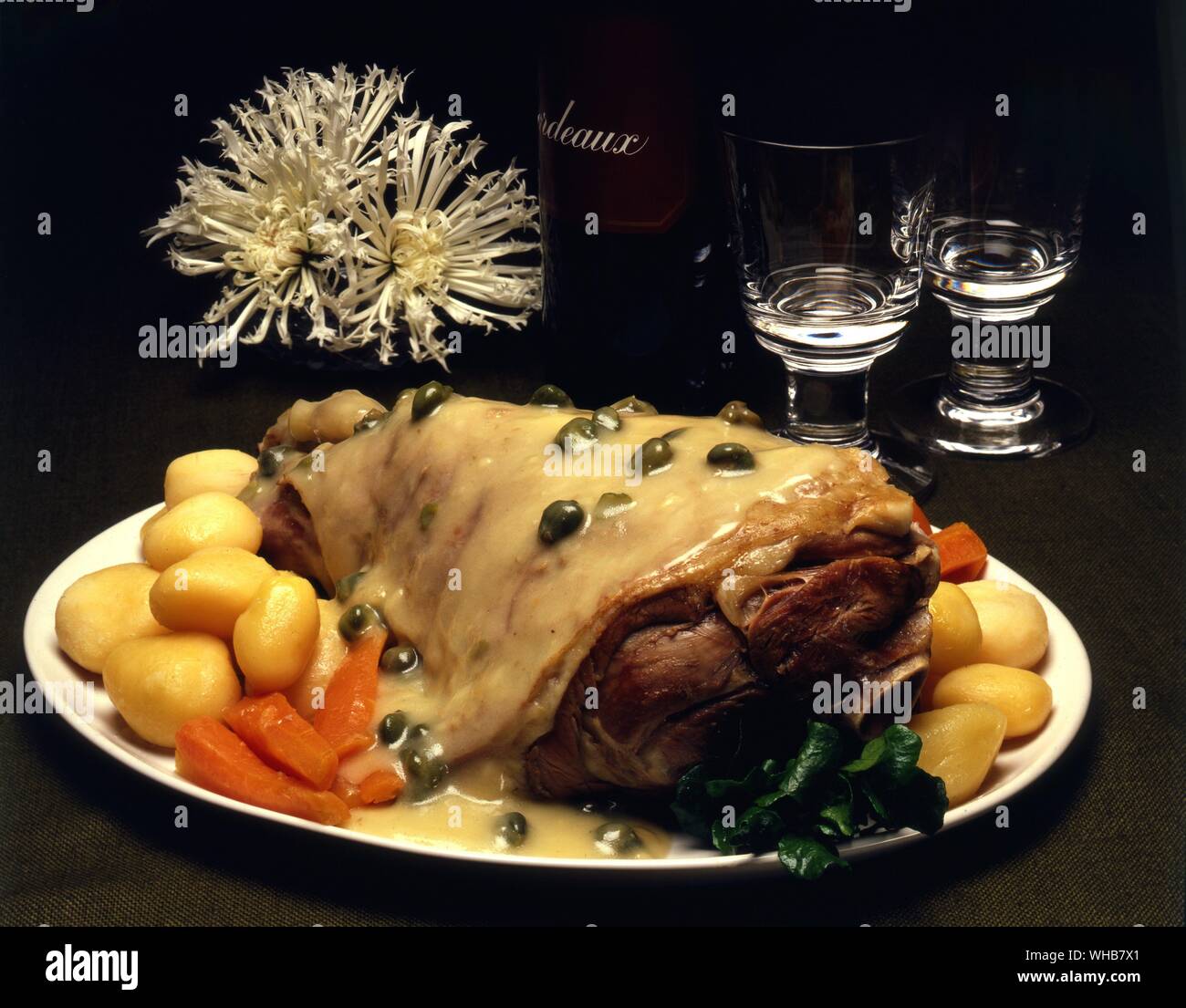 Leg of lamb with potatoes and carrots and covered in a cream peppercorn sauce or gravy. Stock Photo