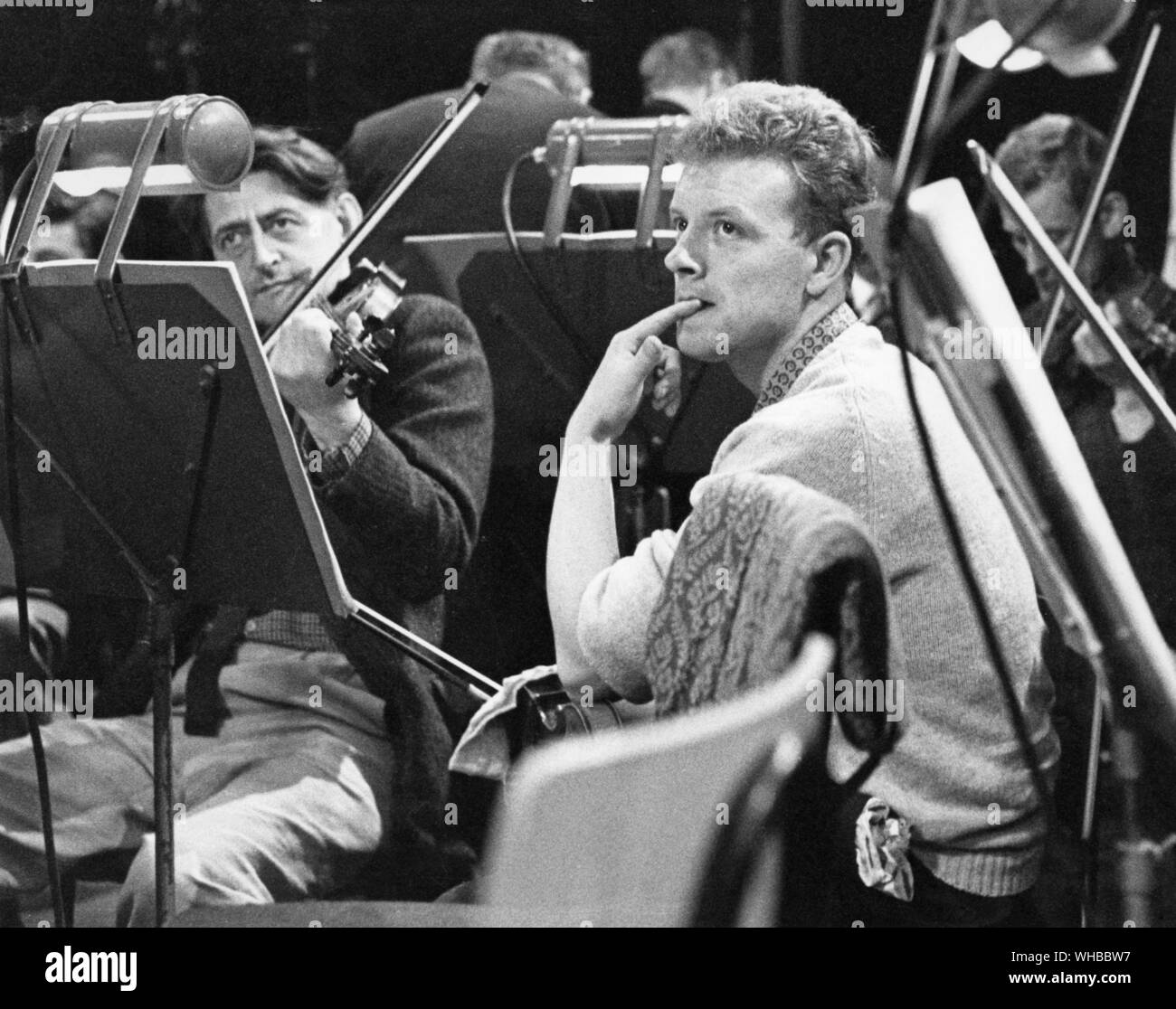 Orchestra - a puzzled violinist watches the conductor during rehearsal.. Stock Photo