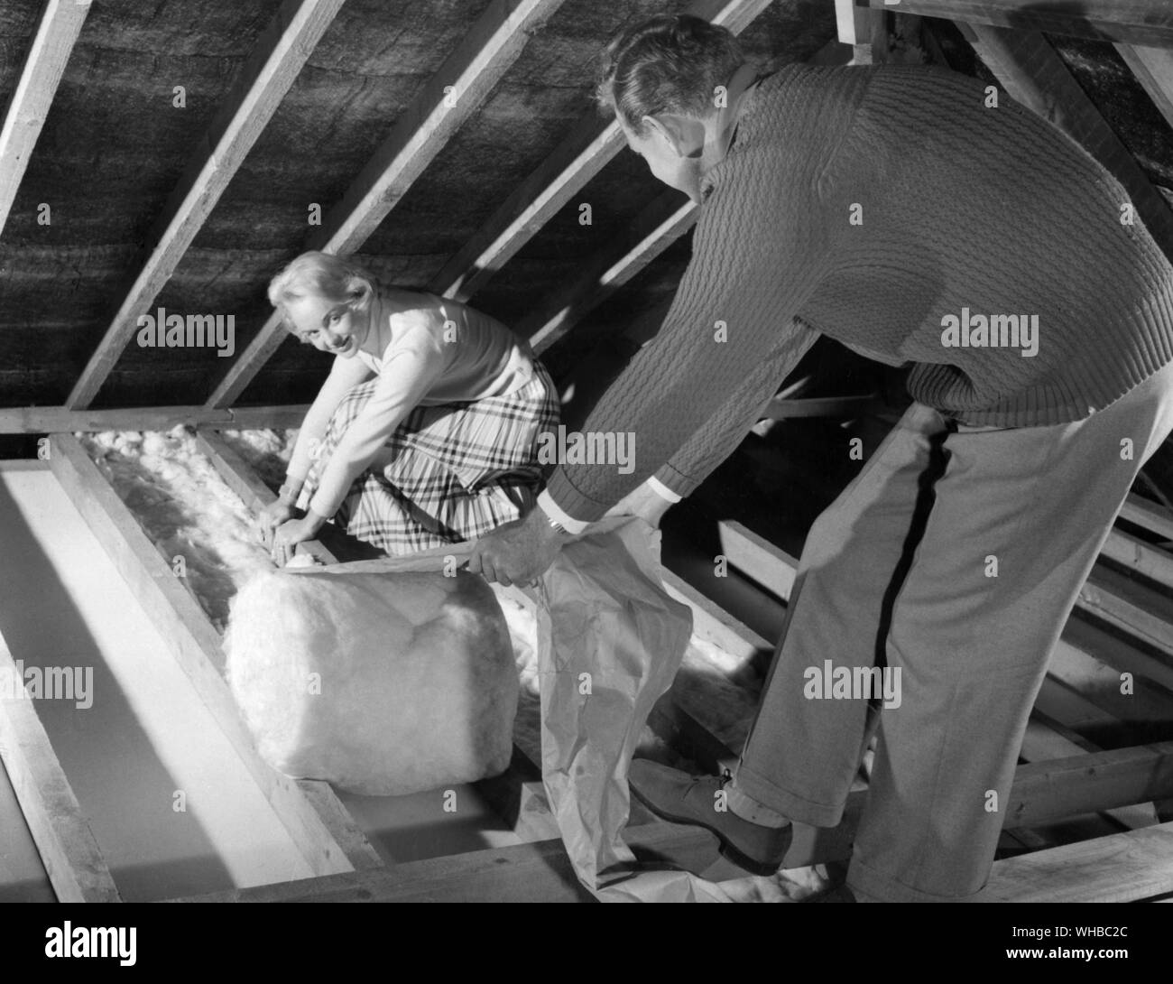 Insulating the roof space with Rocksil Housewarm fibreglass insulation. Stock Photo