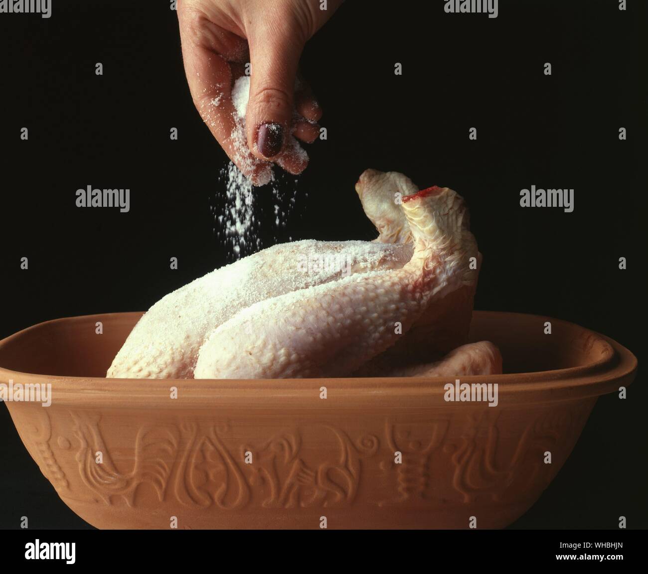 Whole Chicken : Preparing the poultry for roasting and seasoning with salt before cooking in the oven Stock Photo
