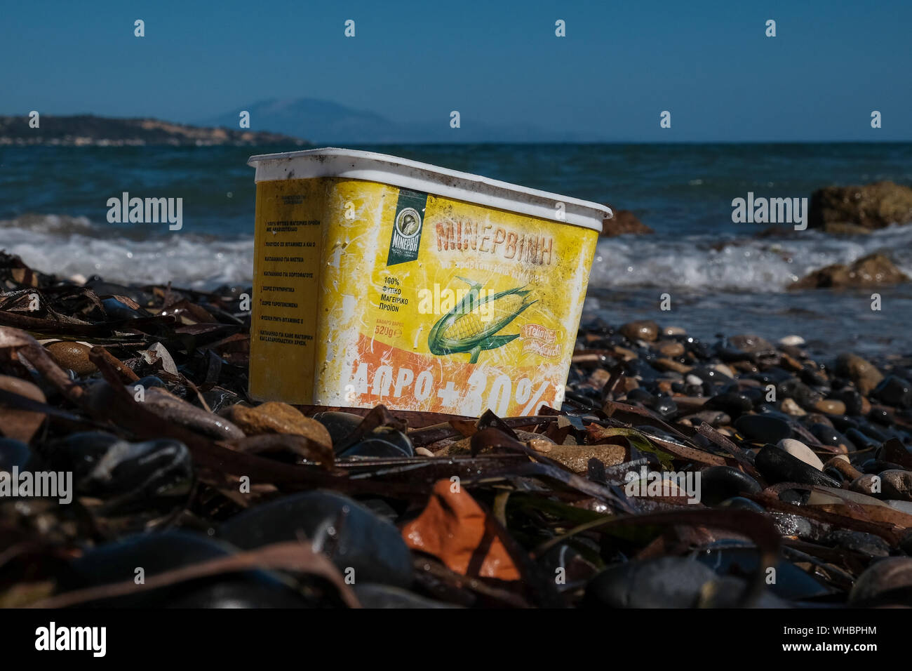 A plastic Sweetcorn container discarded on the beach with water fading and damage adding to the now pollution of the ocean and environment damage. Stock Photo
