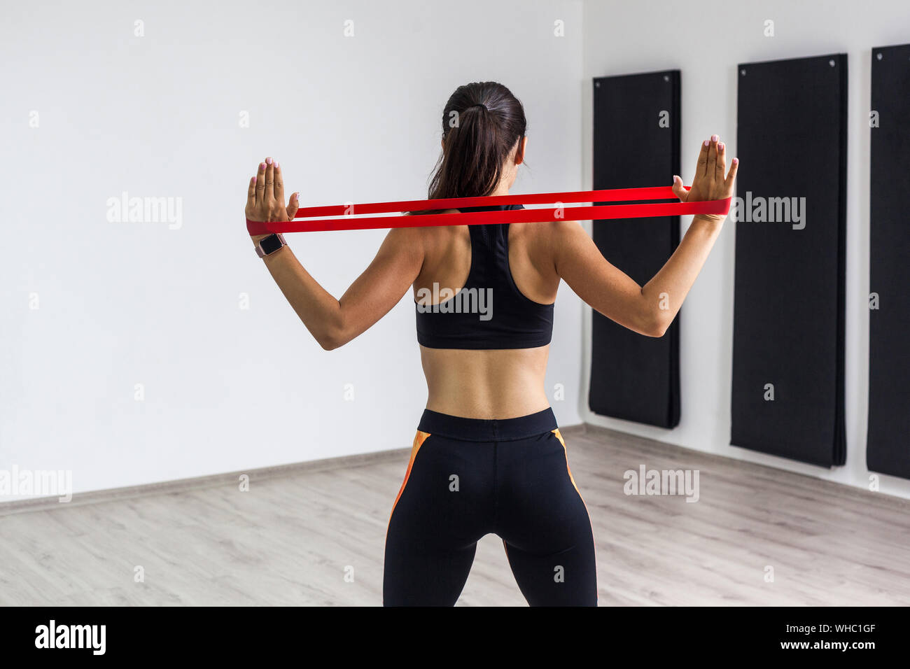 Premium Photo  Rear view of athletic fitness woman in black top and grey  leggings doing exercises for muscles of back and hands with resistance band  during outdoors workout