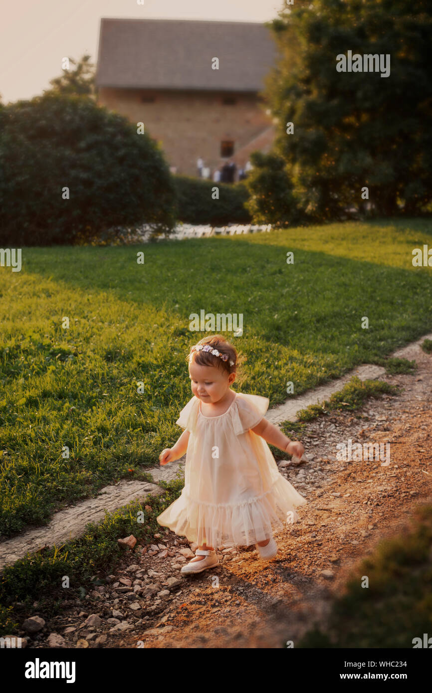 Beautiful little baby girl running in a white dress Stock Photo