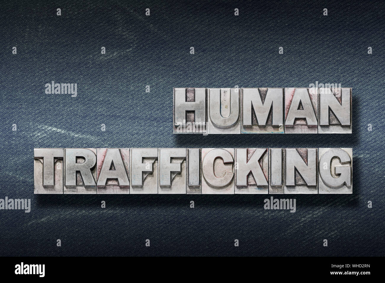 human trafficking phrase made from metallic letterpress on dark jeans background Stock Photo