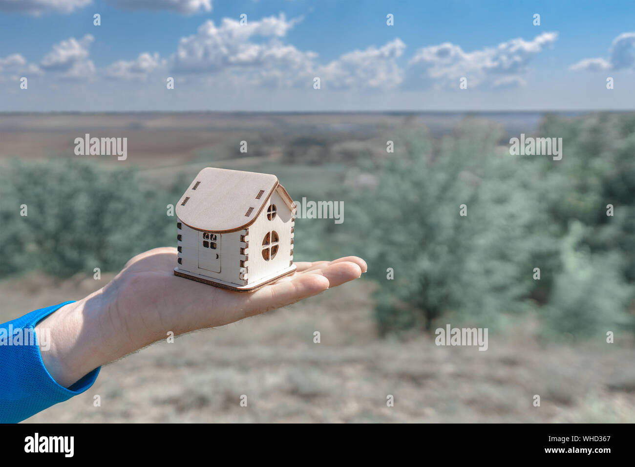 Man holds out a small wooden house in the palm of his hand. Wooden ...