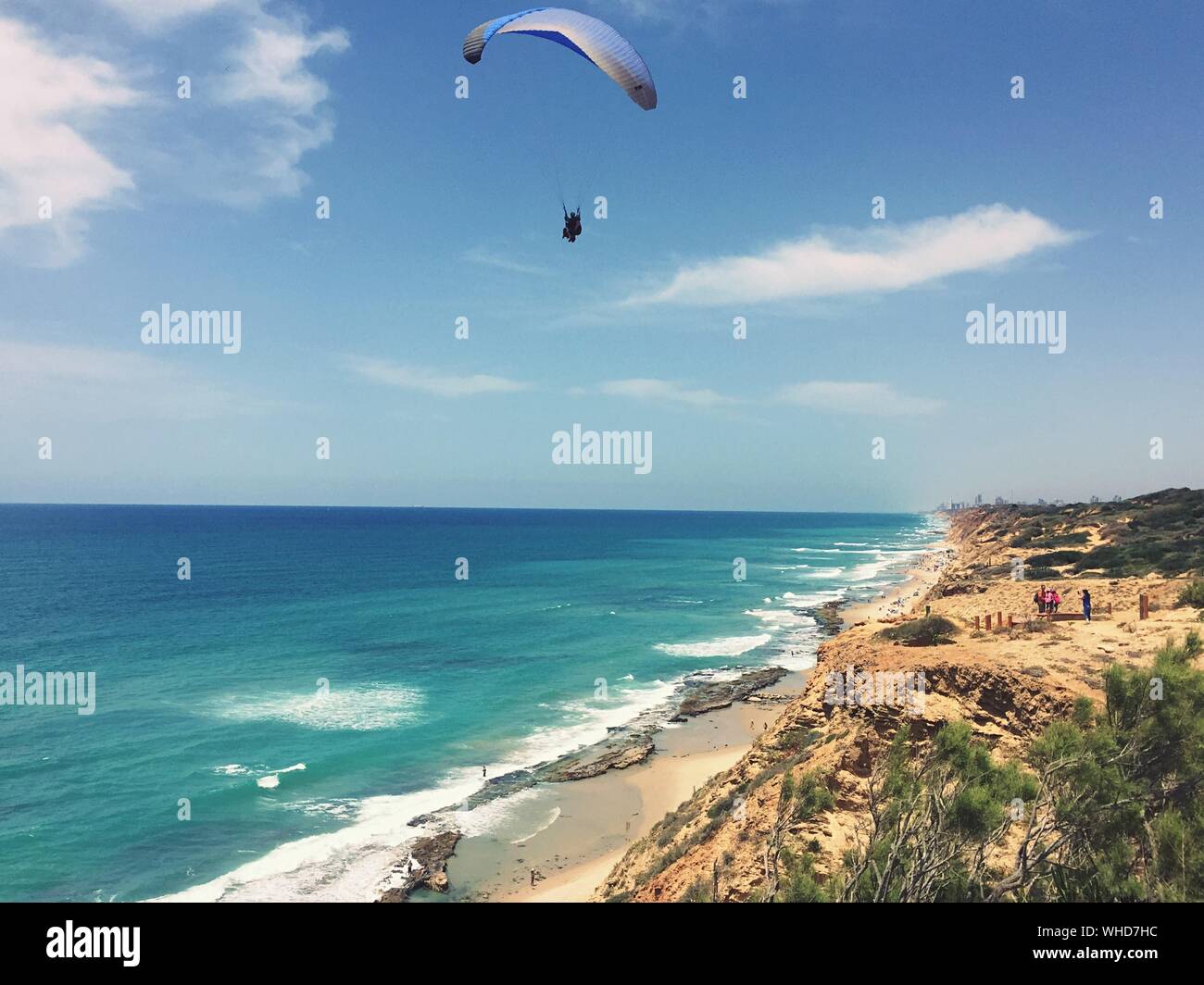 Person Paragliding Over Beach Against Sky Stock Photo