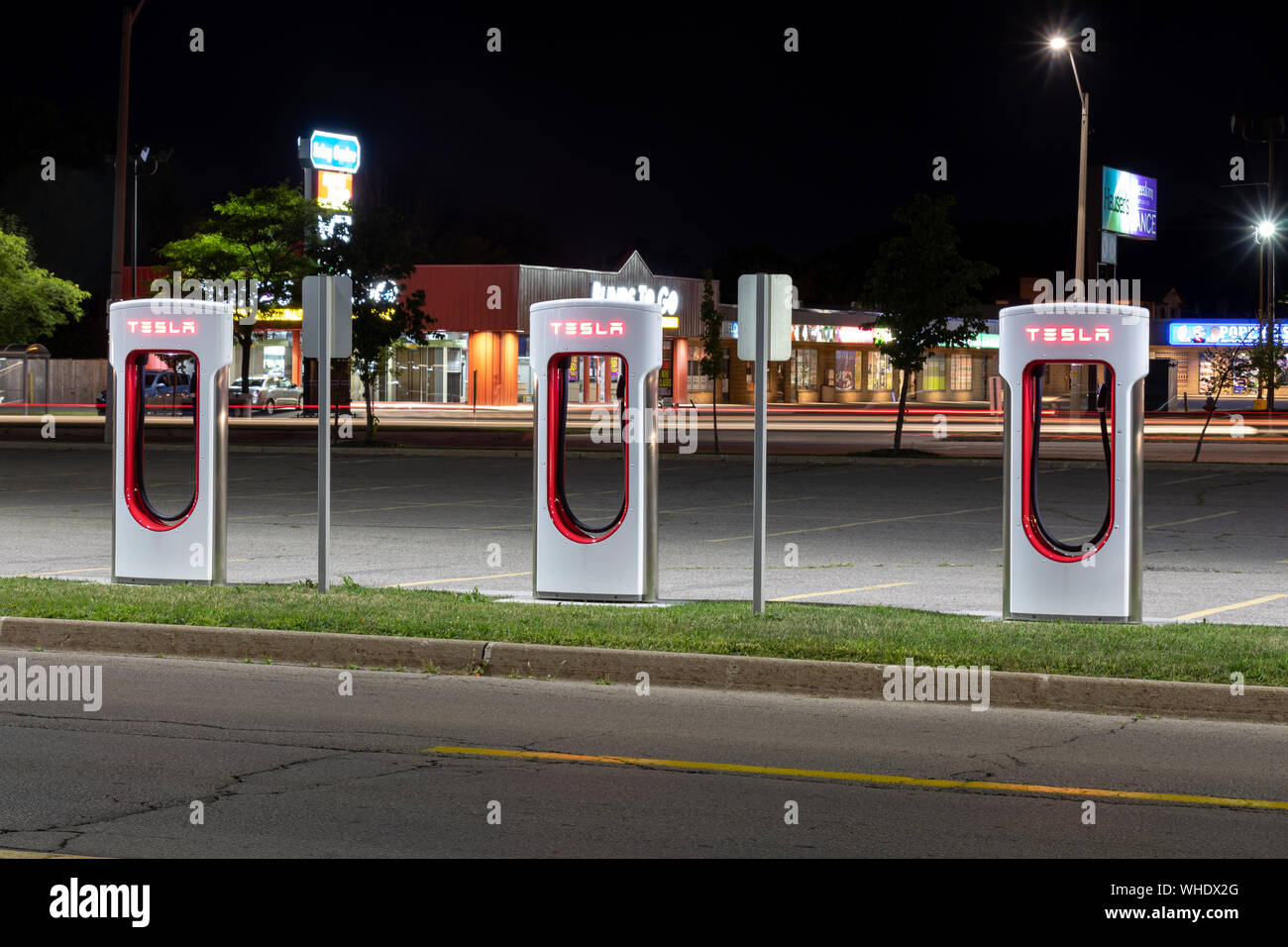 Three Tesla Supercharger Stations seen late at night in-front of a busy ...