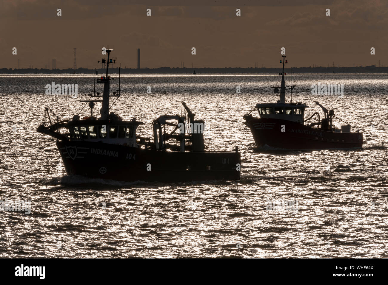 Fishing boats Indianna heading out to sea to fish late afternoon for the night out of Leigh on Sea passing Southend on the Thames Estuary. Industry Stock Photo