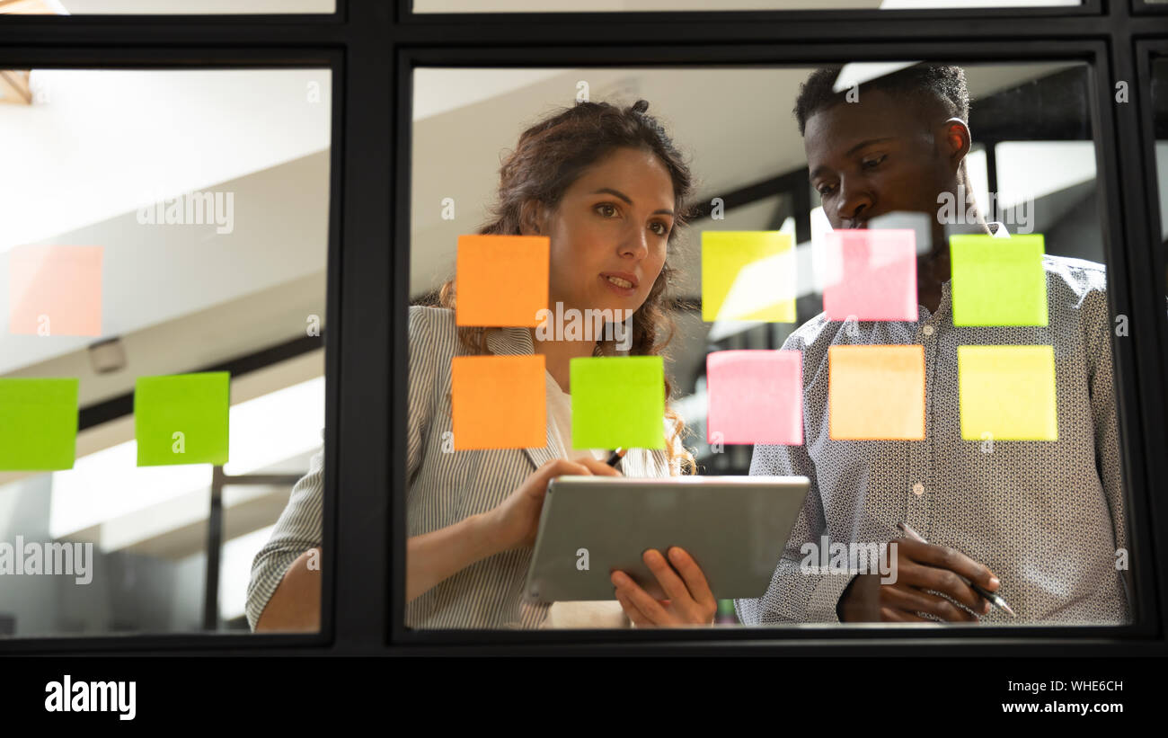 Two serious coworkers checking project plan writing on sticky notes Stock Photo