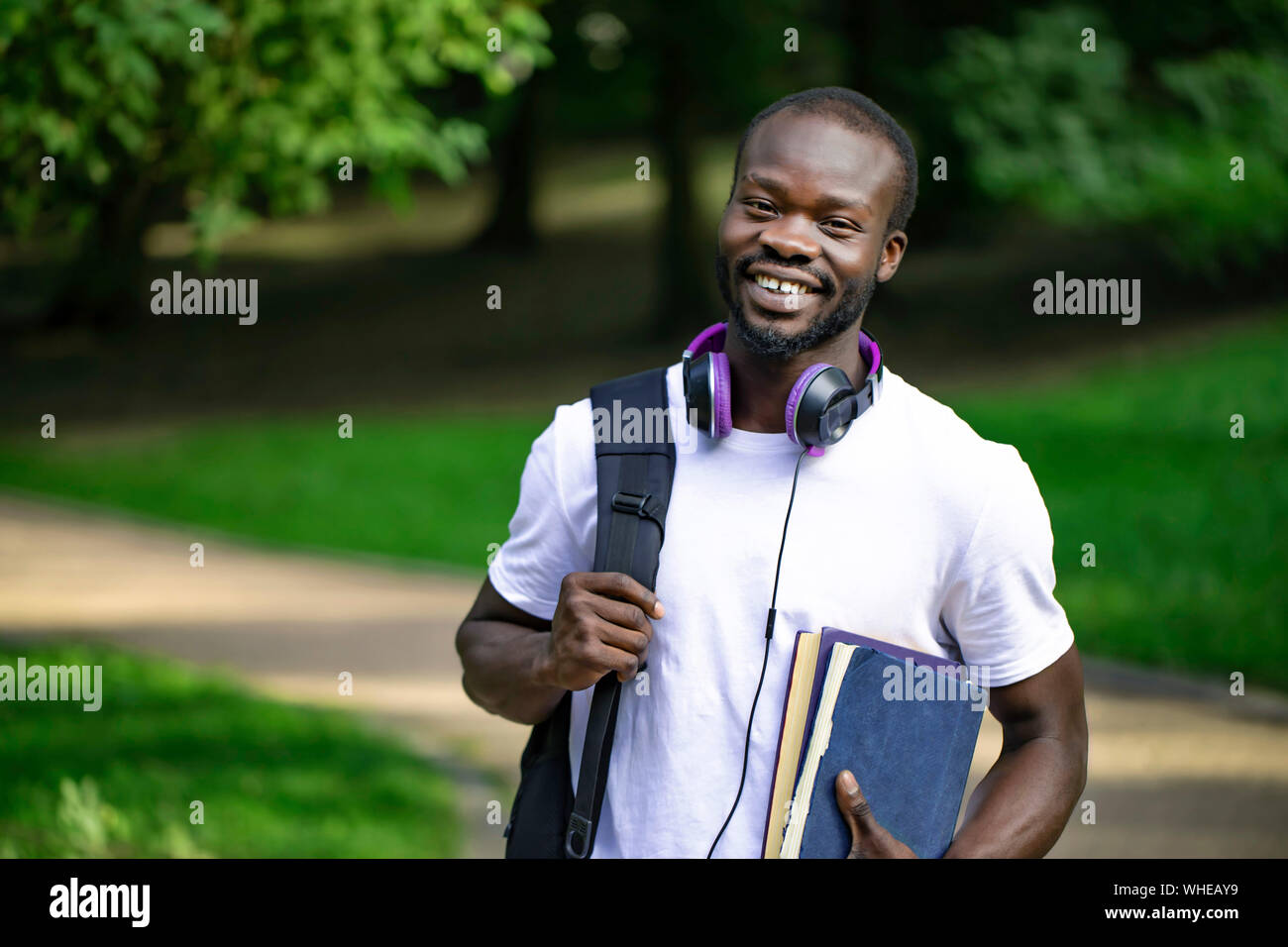 Portrait of smiling African-american student guy on a campus park path Stock Photo