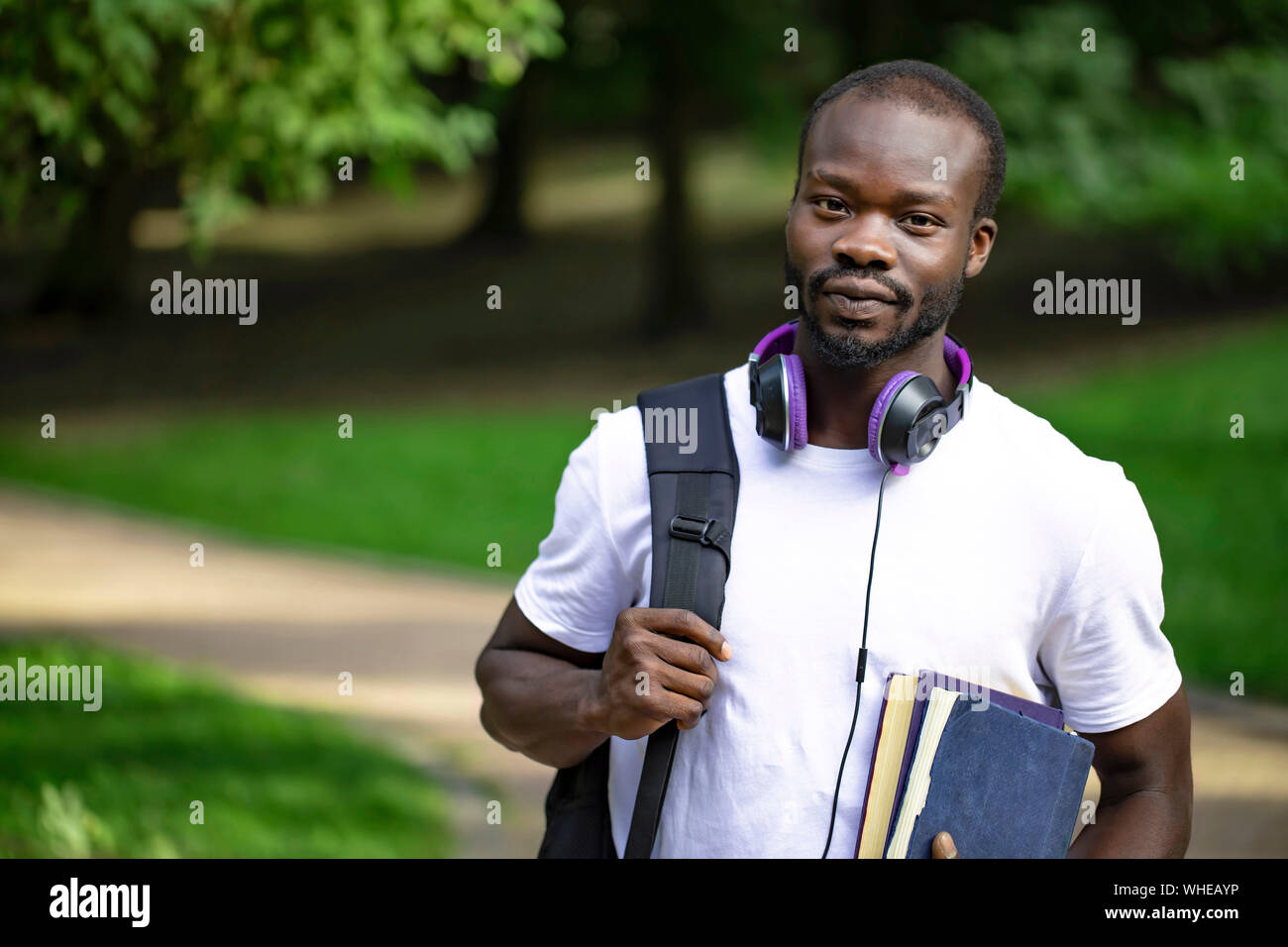 Portrait of a modest african male student on his way to classes through campus park Stock Photo