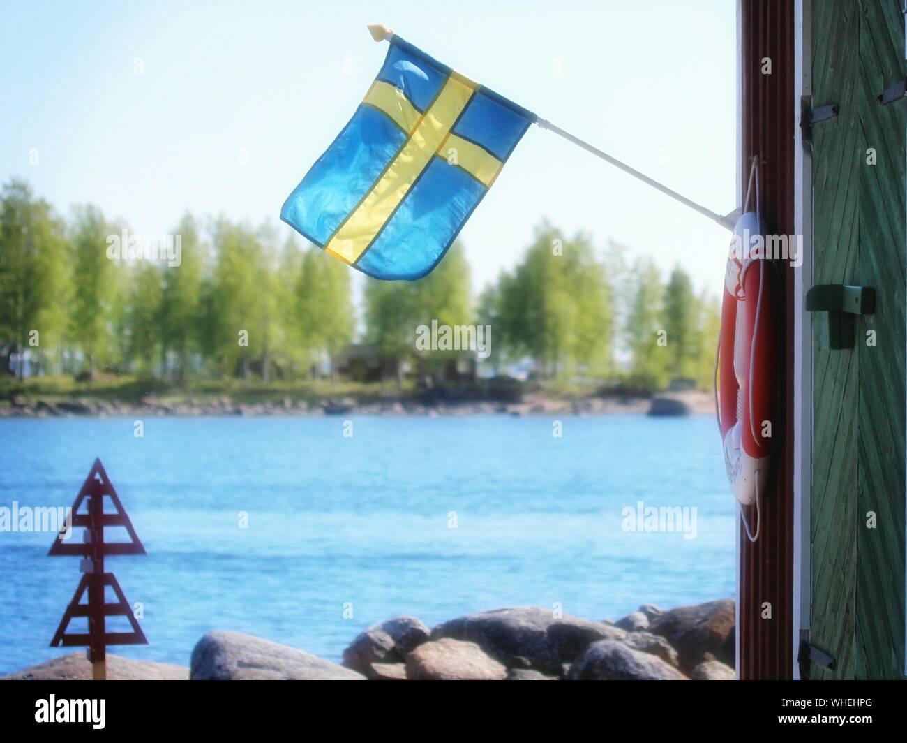 Swedish Flag On Pole By River Stock Photo