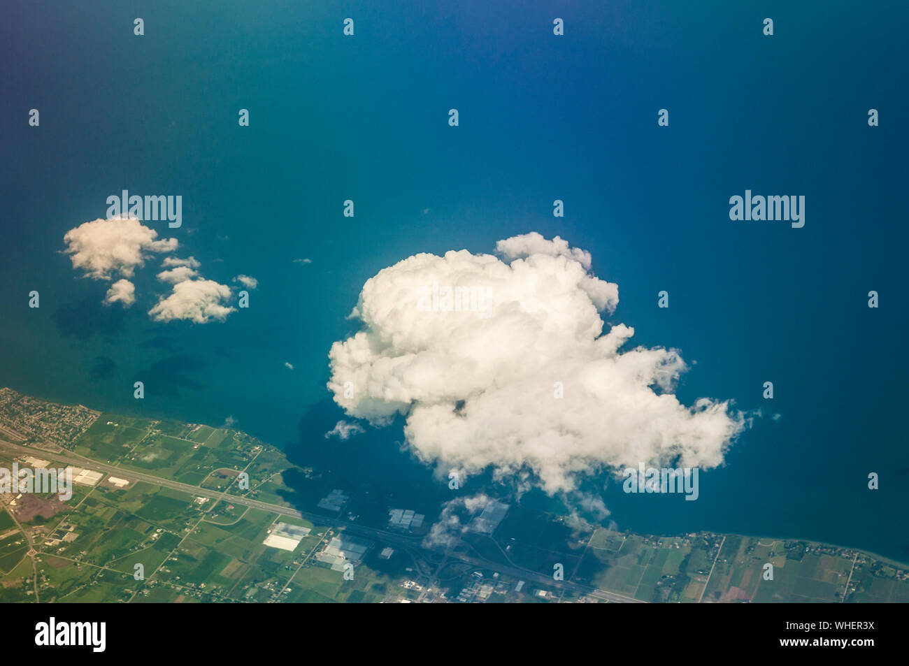 Soft puffy clouds over the Atlantic Ocean on a blue-sky day in summer. Photographed from a regular commercial flight window seat.  35000 feet. Stock Photo