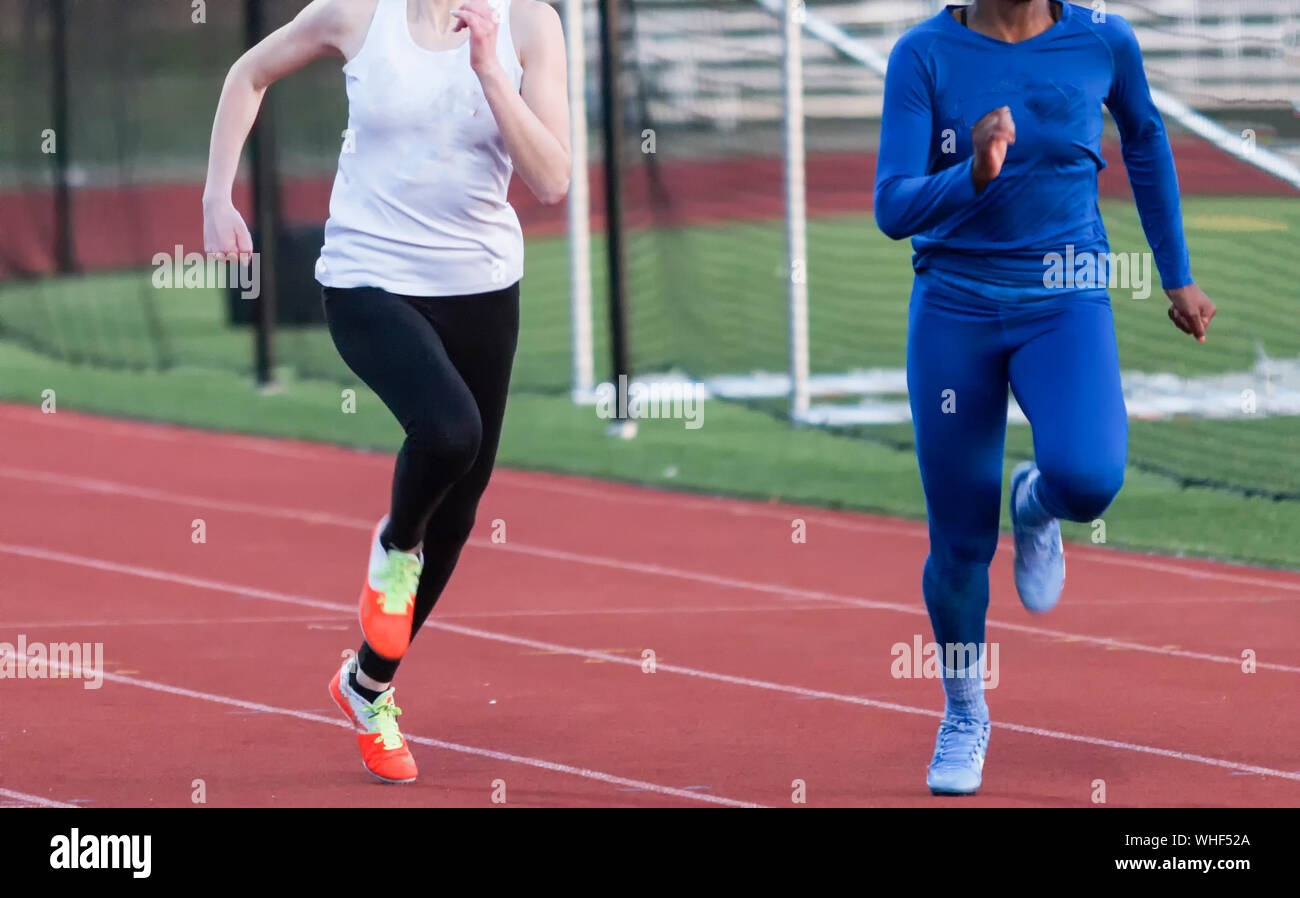 Two high school girls wearing spandex on their legs suring a race because it is early spring and cold. Stock Photo