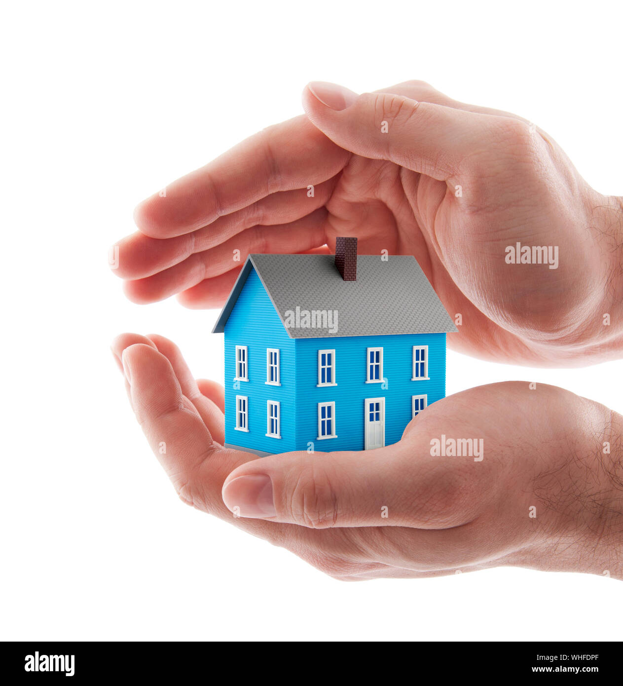 Small blue toy house protected by hands isolated on white Stock Photo