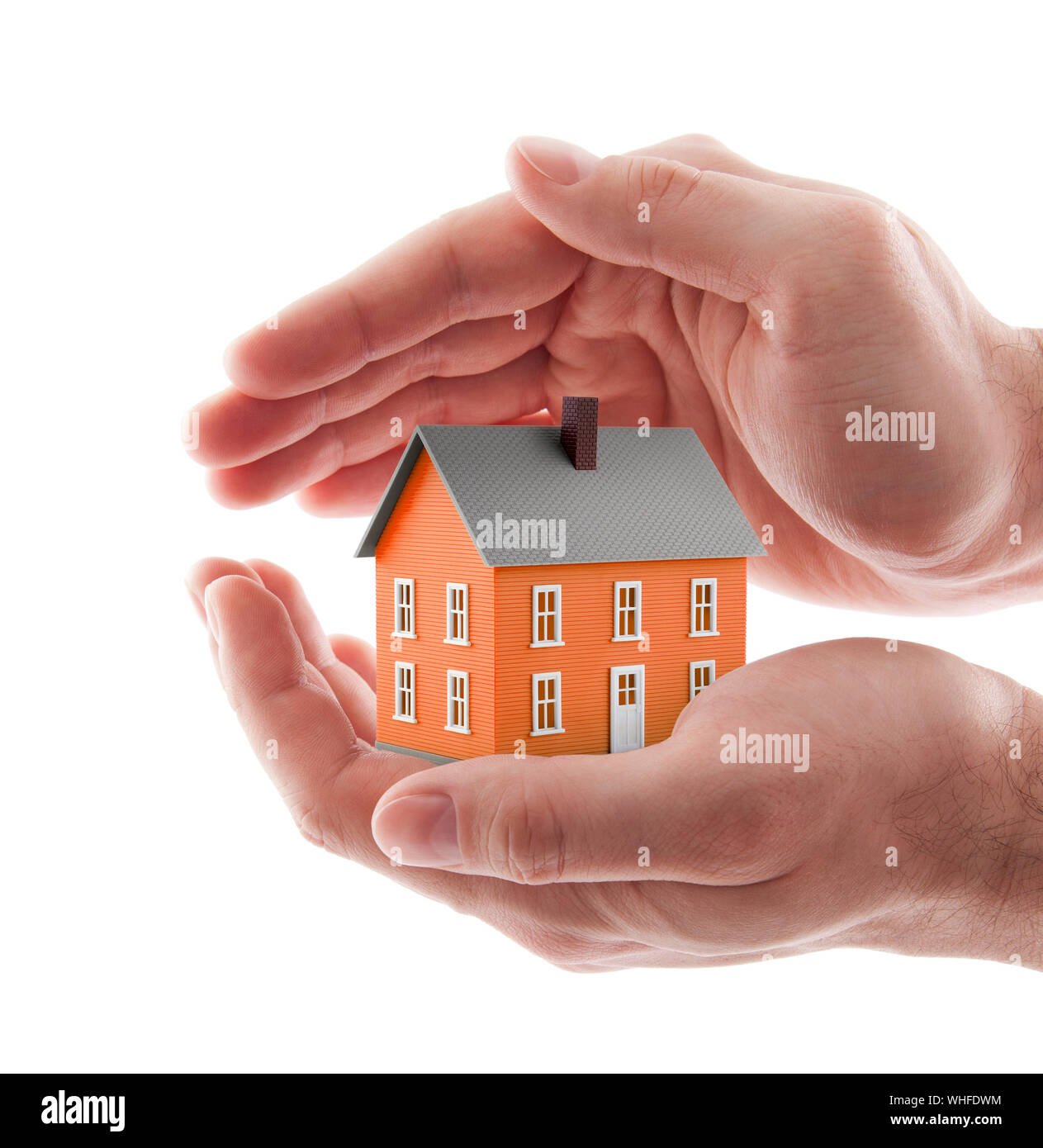 Small orange toy house protected by hands isolated on white Stock Photo