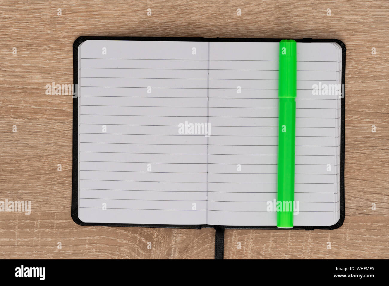 Open notebook with green marker on desk Stock Photo