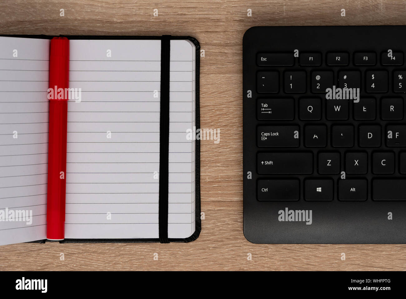 Pen on open notebook with black keyboard Stock Photo