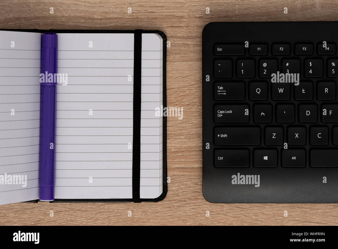 Blue pen on open notepad with keyboard Stock Photo