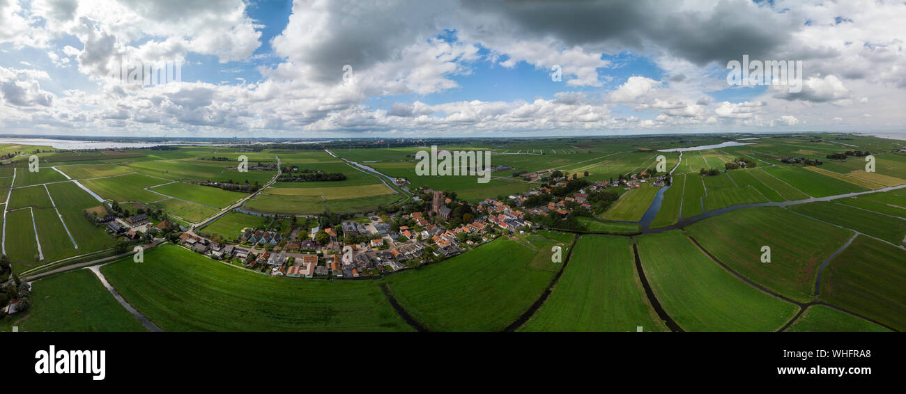 Dramatic aerial panoramic view of the agrarian green pasture fields with its irrigation infrastructure of ditches and trenches surrounding Stock Photo