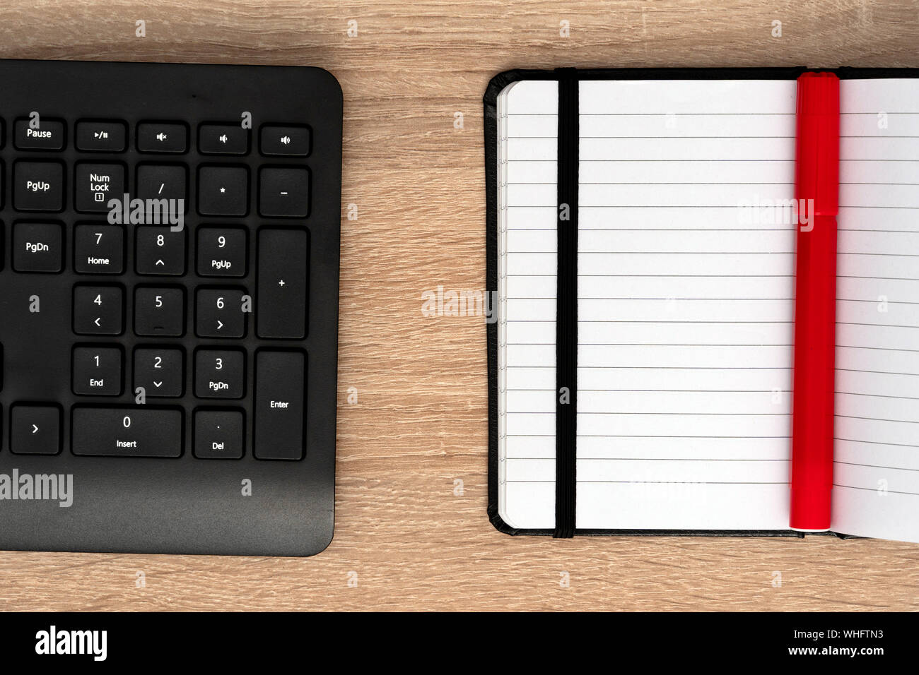Red pen on notepad with black keyboard Stock Photo