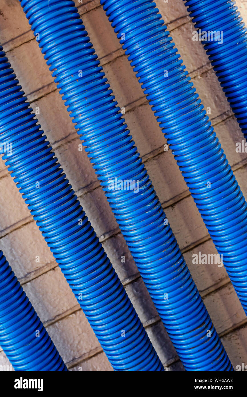 Corrugated blue plastic conduits with clips against a wall Stock Photo