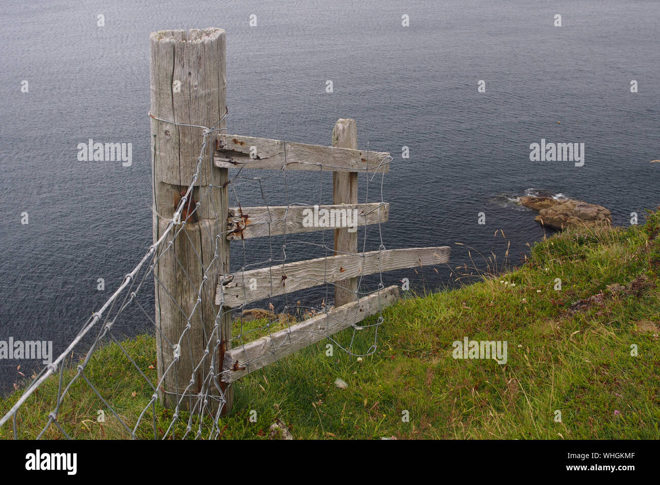 A view out to sea at the end of the stoer peninsula, Sutherland, Scotland with a fence post and fence end pointing down the cliff to the sea Stock Photo