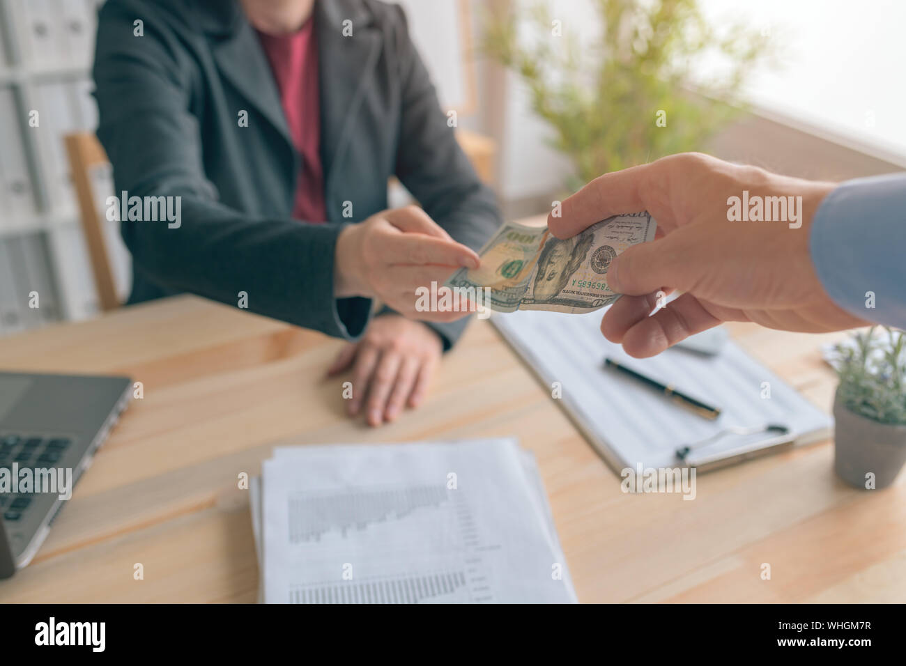 Business corruption, man passing 100 dollar bill to woman in business office, hush money and bribery concept Stock Photo