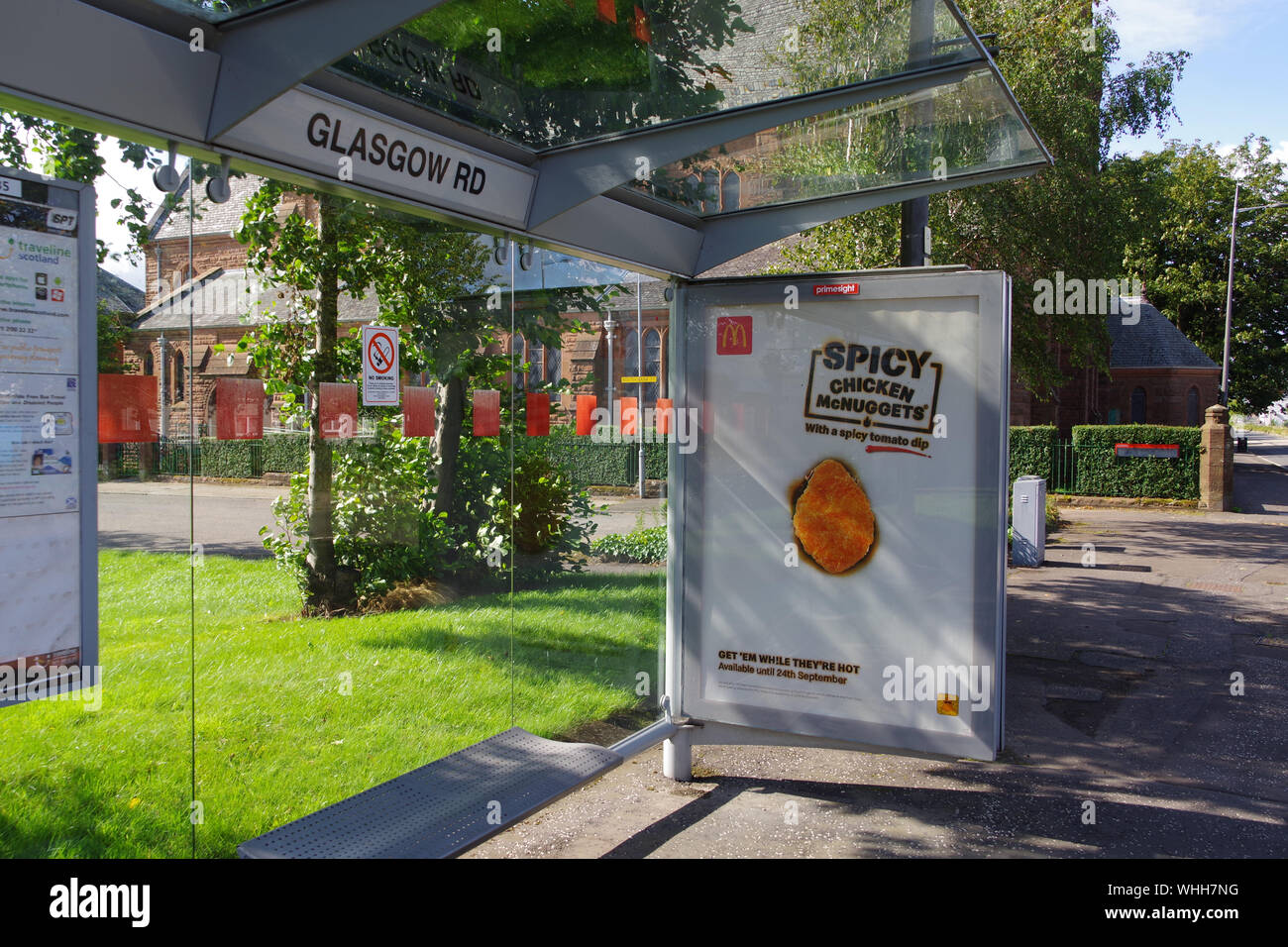 Bus shelter on Glasgow Road, Clydebank, with McDonald's Spicy Chicken McNuggets advert displayed. Stock Photo