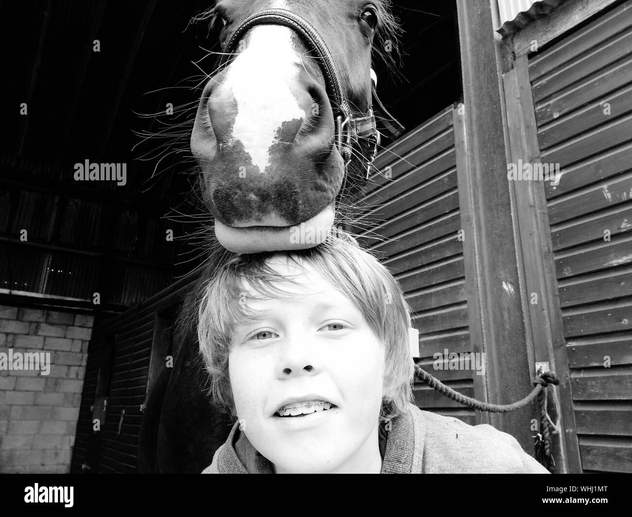 Portrait Of Boy With Horse At Stable Stock Photo