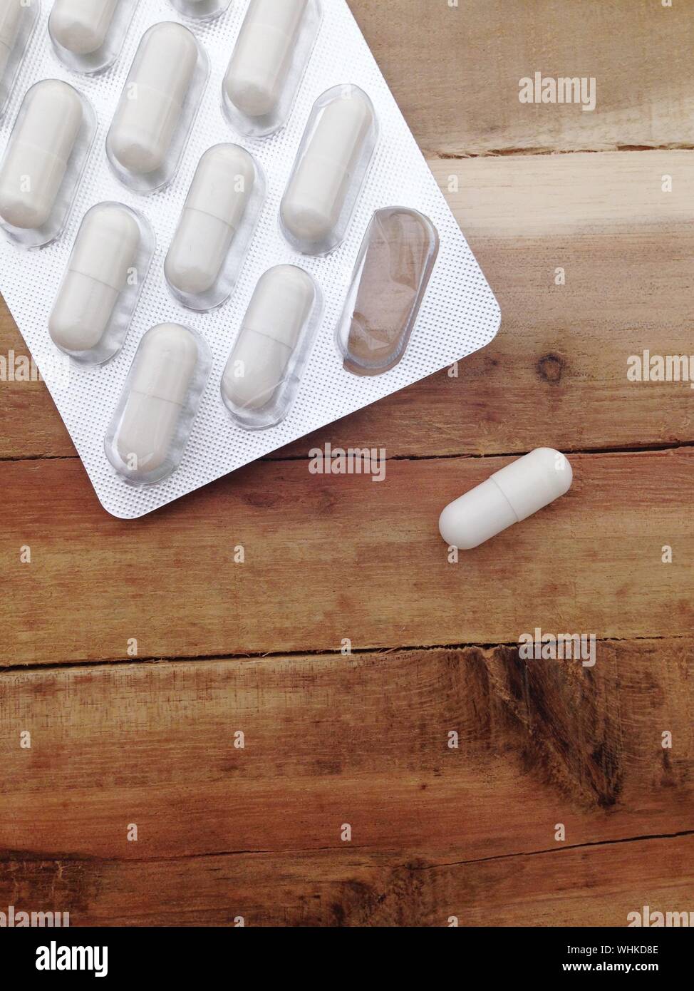 High Angle View Of Capsule Removed From Blister Pack On Wooden Table Stock Photo