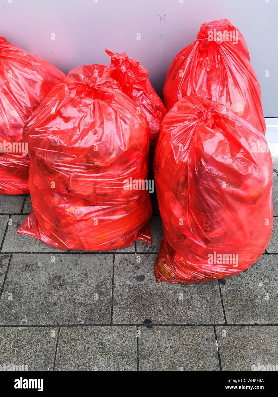 Red Garbage Bags On Footpath Against Wall Stock Photo - Alamy