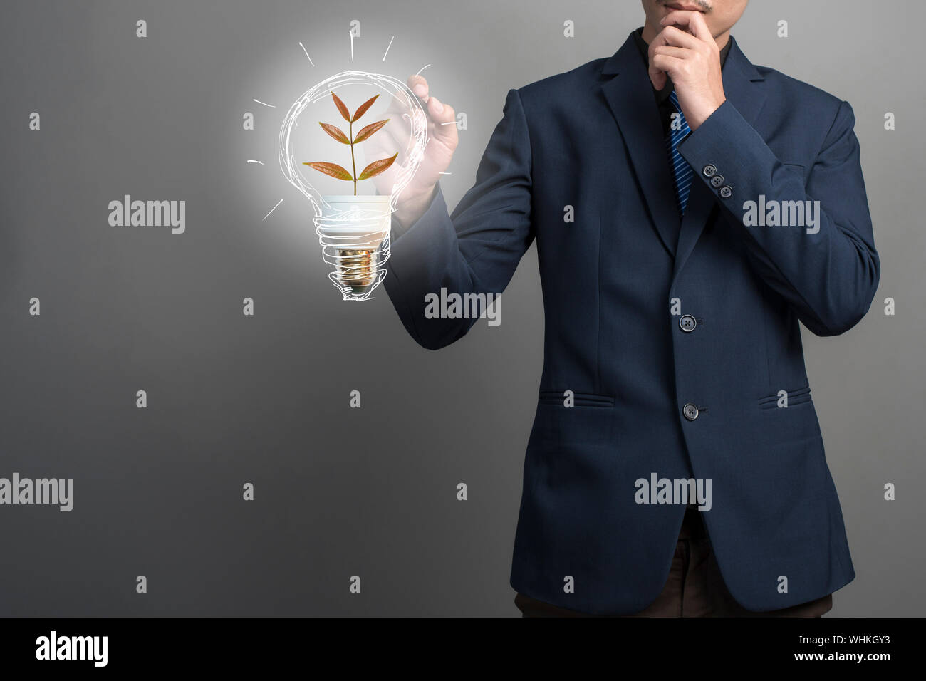 Midsection Of Businessman Pointing At Illustrative Bulb While Standing Against Gray Background Stock Photo