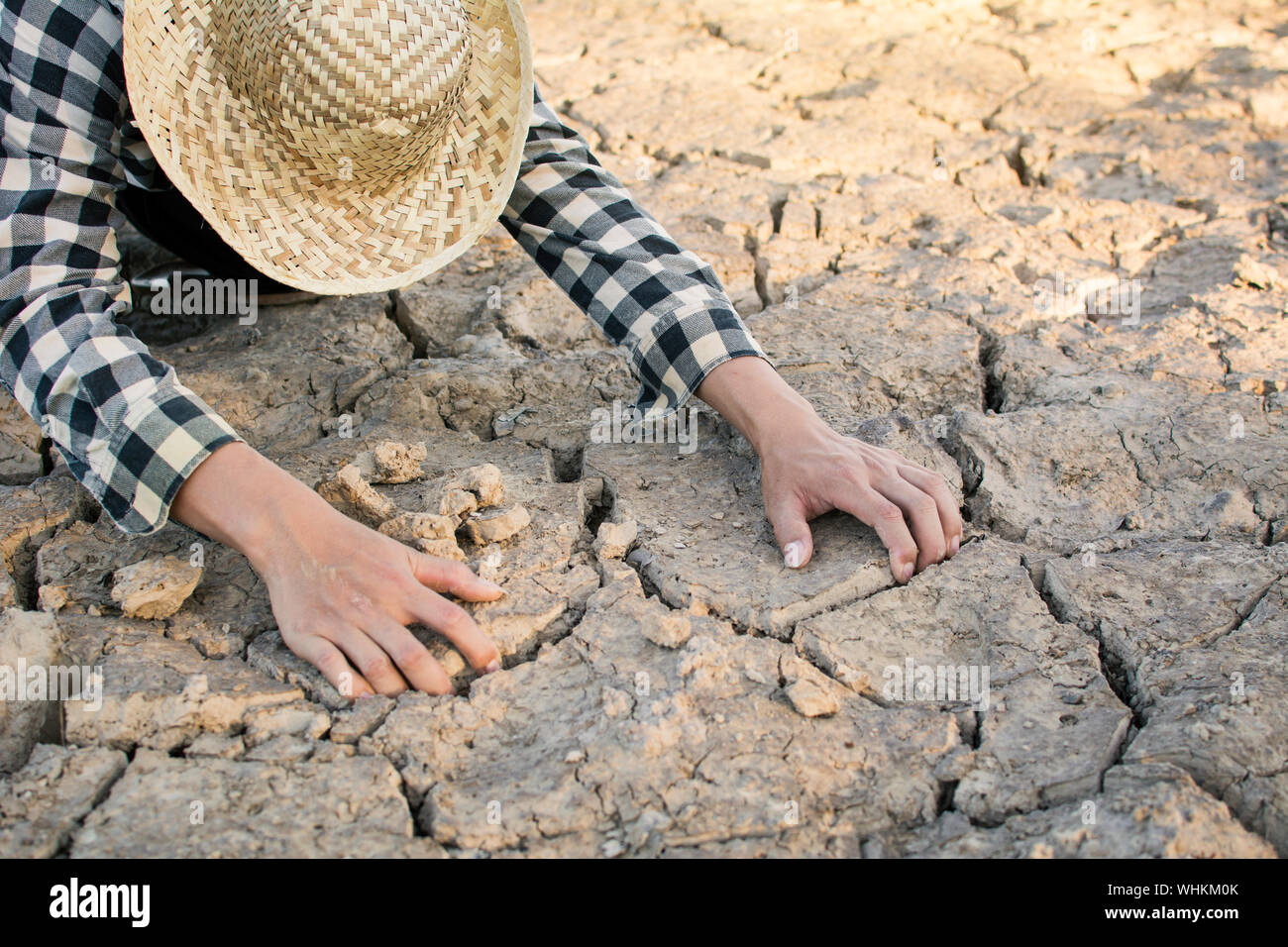 Person Kneeling On Cracked Field Stock Photo