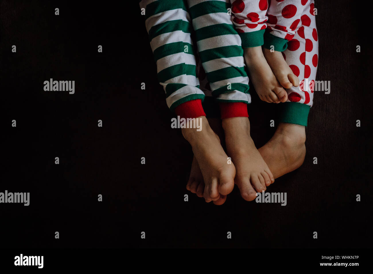 Low Section Of Family In Pajamas Against Black Background Stock Photo