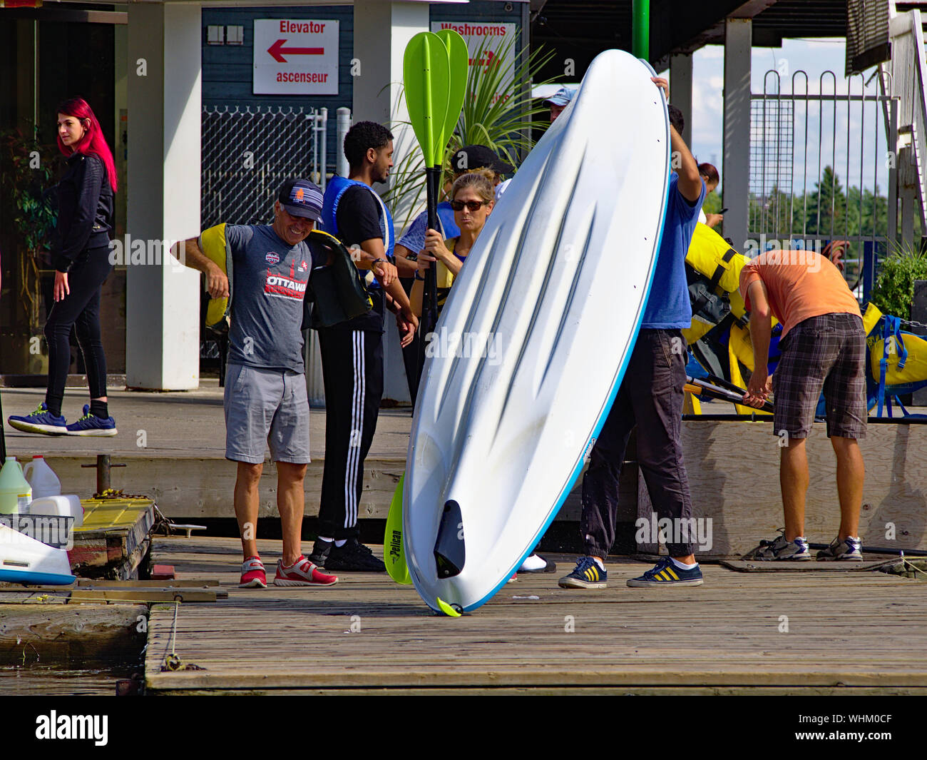 Boat rental crew launch a kayak as holidaymakers don life jackets and choose paddles. Dow's Lake