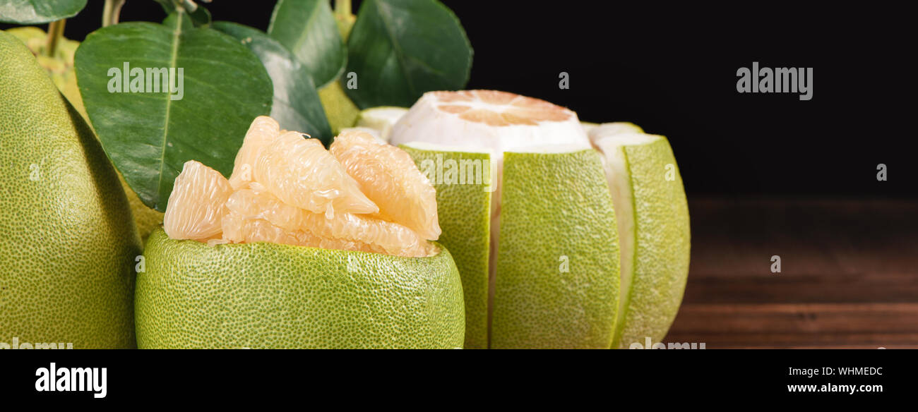 Fresh peeled pomelo, grapefruit, shaddock with green leaves on dark